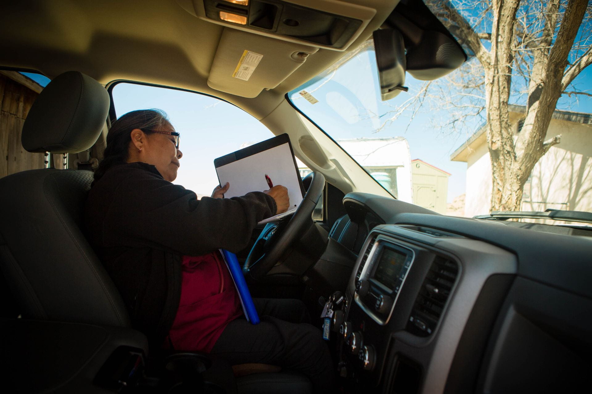 community health worker taking notes on the steering wheel of her car
