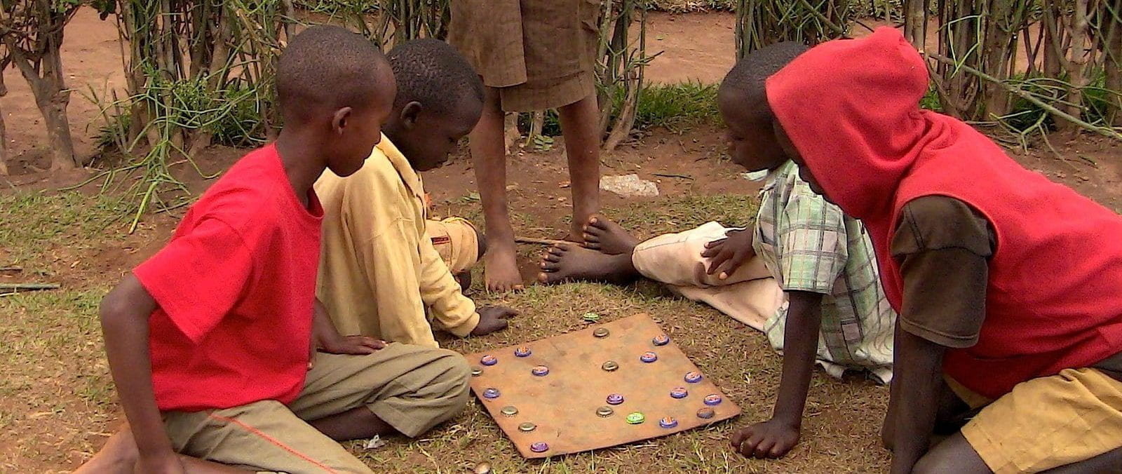 four kids playing team chess in rwanda